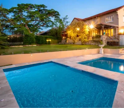 Crest tanning ledge — extra-wide sun shelf installed poolside at dusk