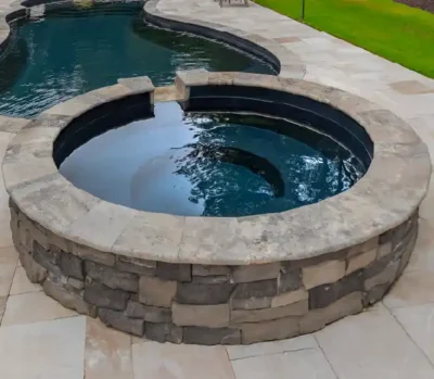 Cove Spa — round fiberglass spa with stone surround and spillover