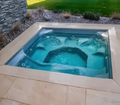 Sanctuary Spa — contoured fiberglass spa with raised stone spillover into pool